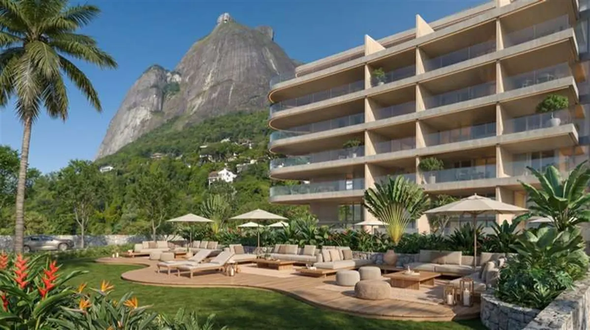 Piscina com deck de madeira e palmeiras, com a fachada escalonada do Vista Joá ao fundo